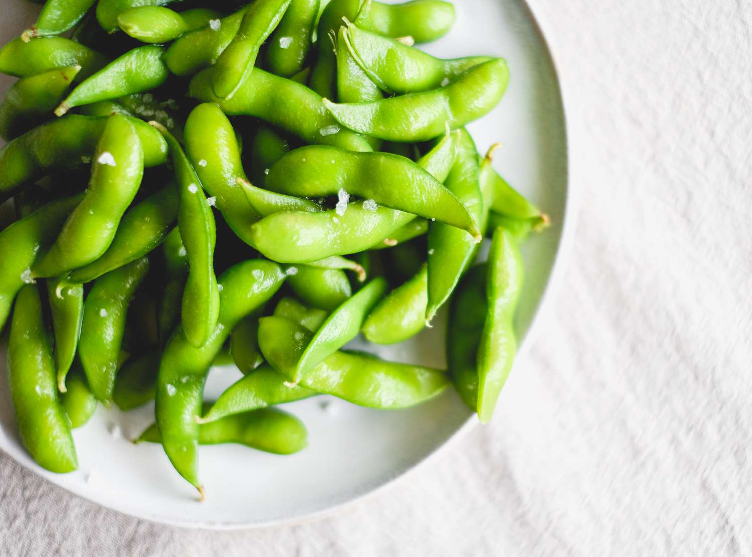 edamame pods sprinkled with salt on plate.