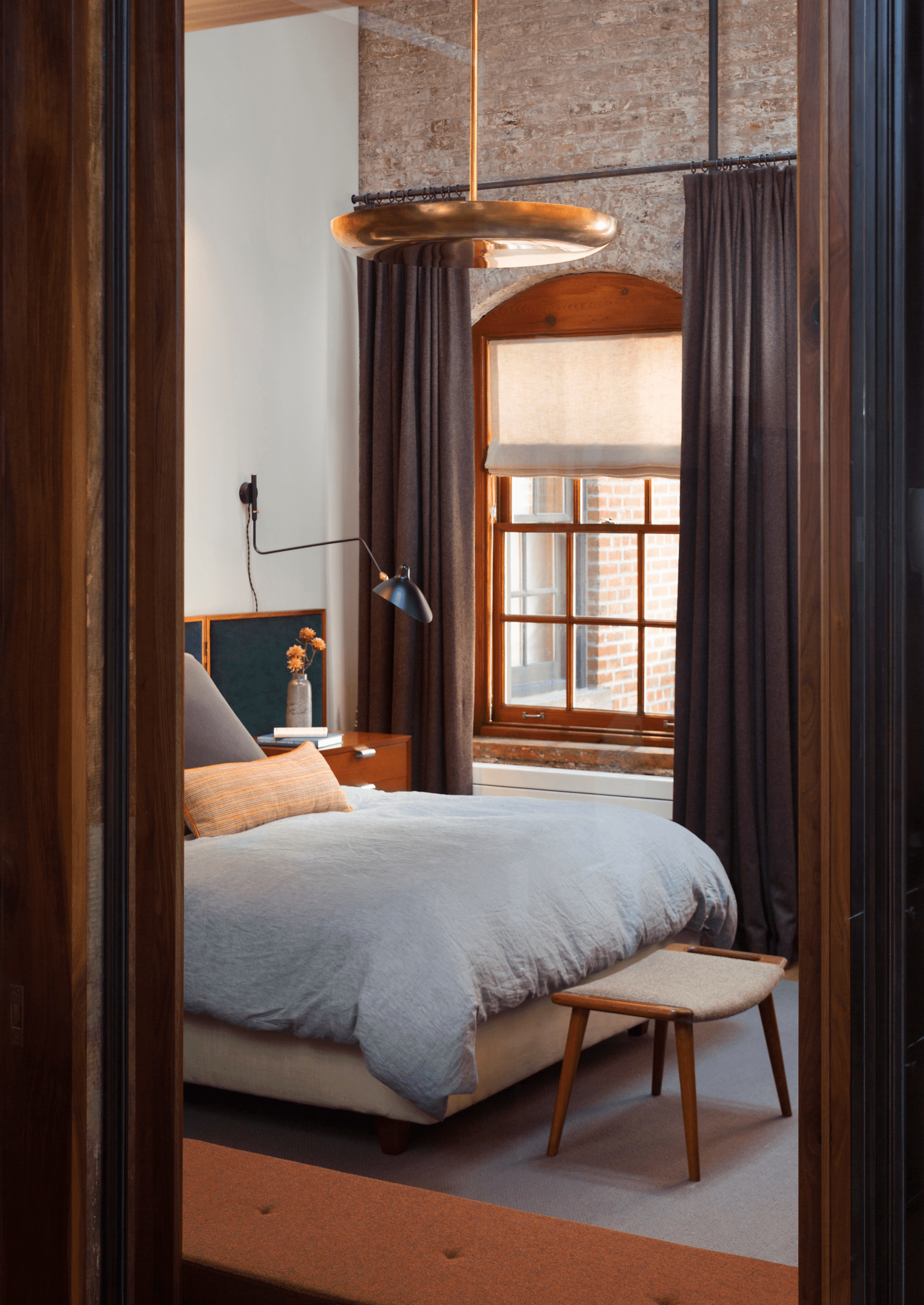 a bedroom with a beautiful brass pendant light