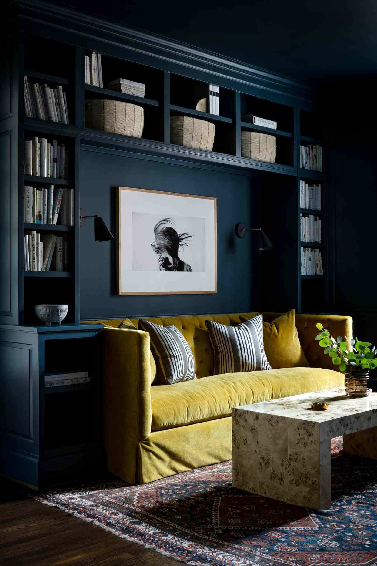 floor to ceiling navy blue wall shelving book case with yellow couch