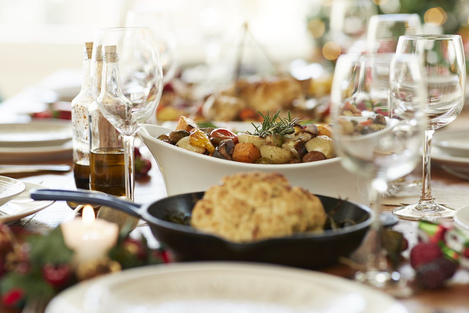 A festive table setting with dishes including roasted vegetables and bread accompanied by wine glasses and condiments