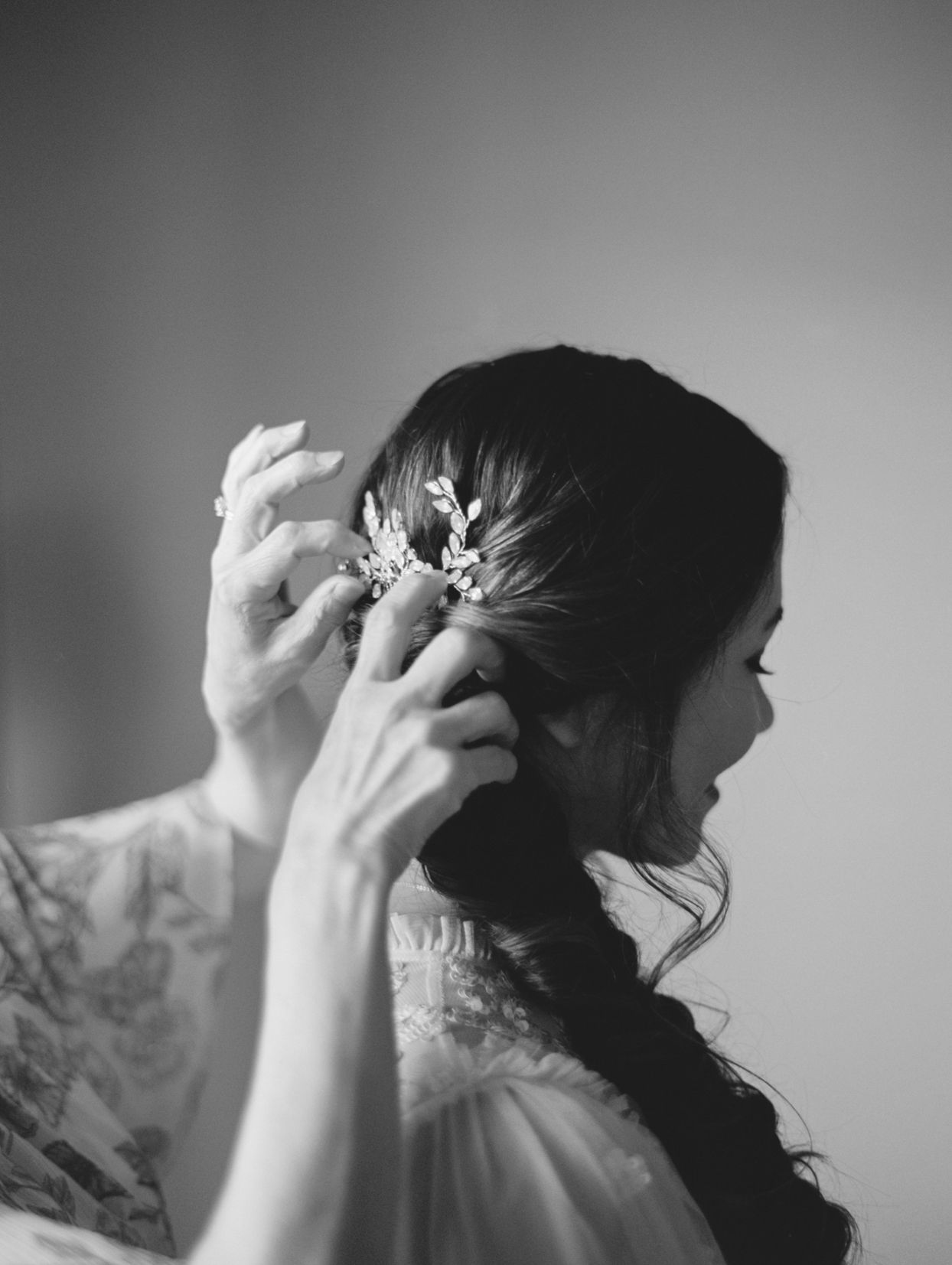 mother putting decorative clip in bride's hair