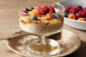 A glass serving bowl of chia pudding topped with assorted berries on a decorative plate