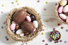 A table with chocolate Easter eggs and colorful candies placed in nests and bowls