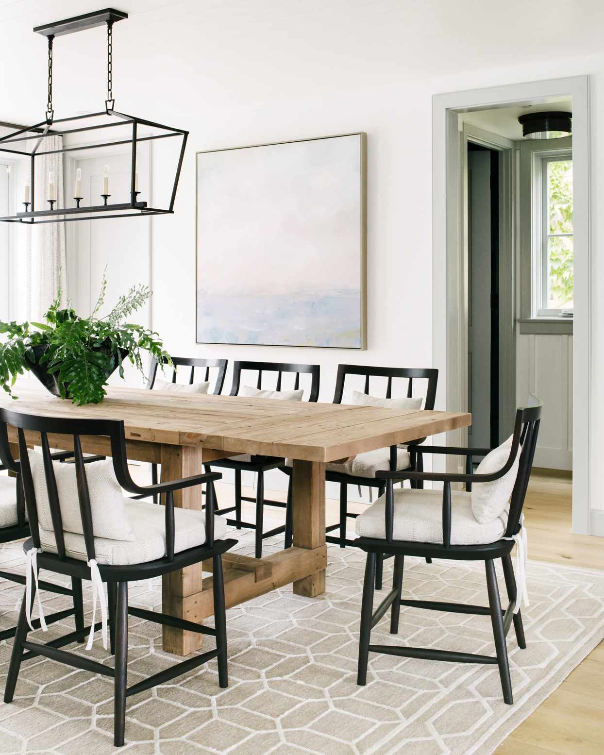 unfinished wooden dining table with black wooden chairs and cream colored cushions