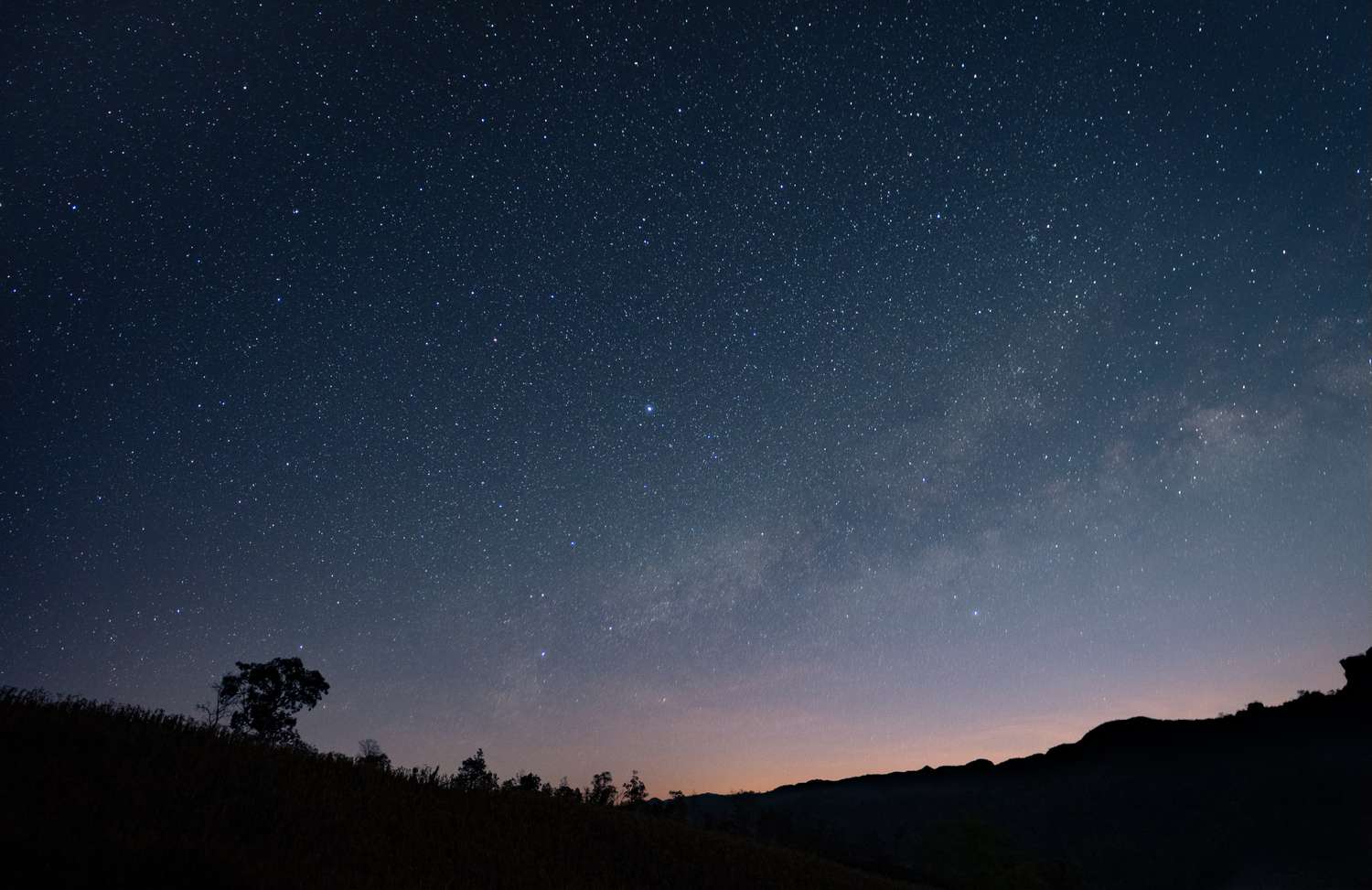 Starfilled night sky above a silhouette of hills and trees a serene astronomical view