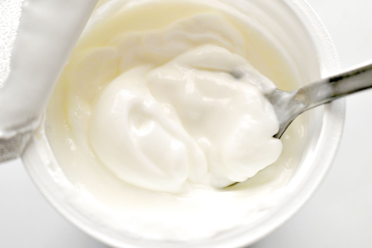 Top view of yogurt in a cup with a spoon inserted