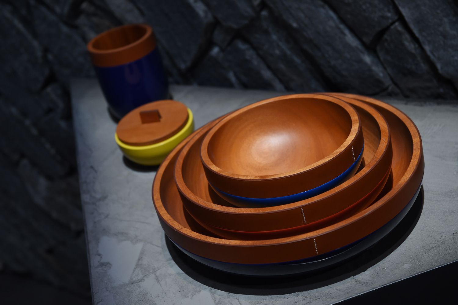 Stacked wooden bowls on a stone table with a pair of nearby small jars