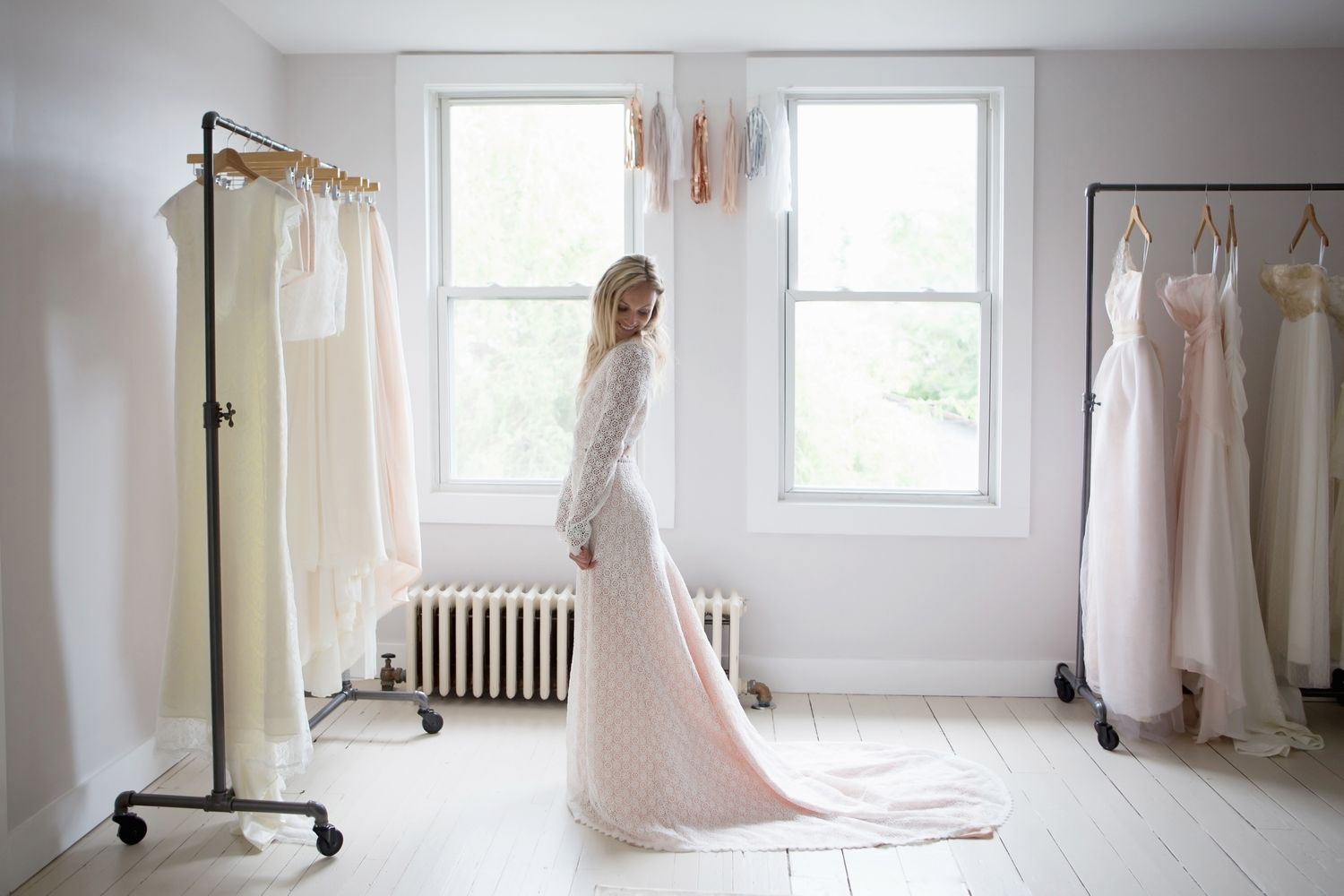 A woman in a bridal gown standing in a showroom with other dresses on racks