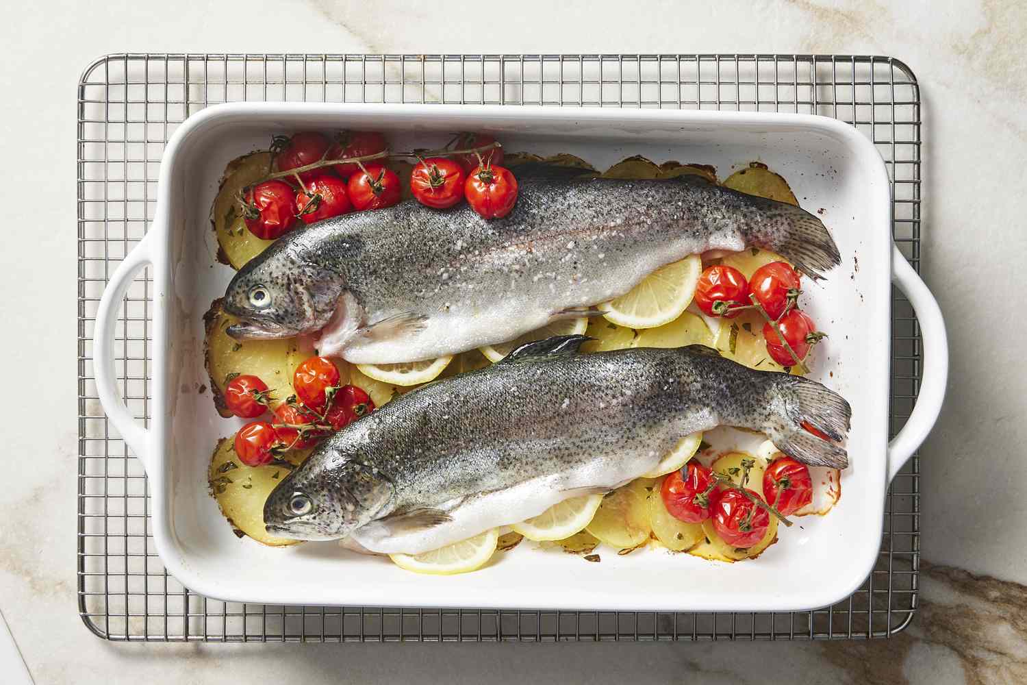 Whole roasted trout with cherry tomatoes and lemon in baking dish