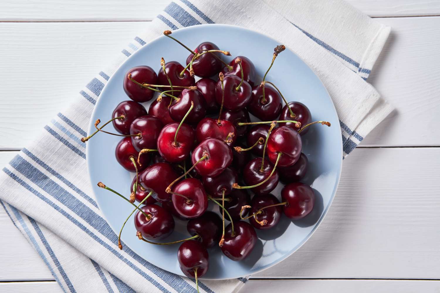 cherries on blue plate with blue and white cloth