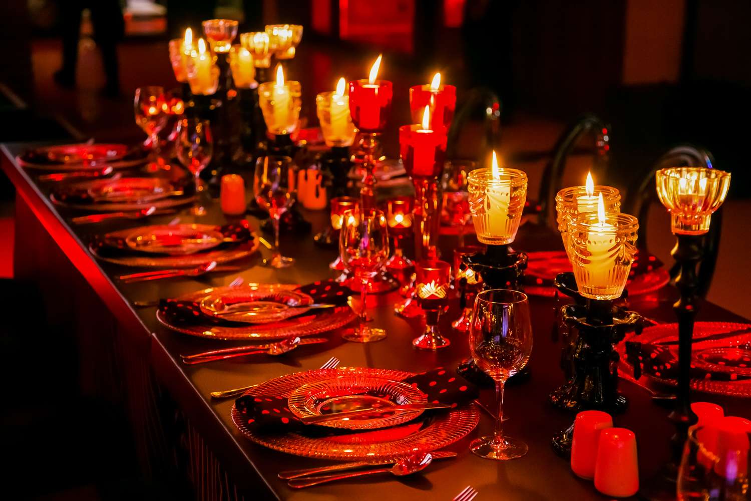 A long dining table set with plates glassware and lit candles creating an elegant and intimate atmosphere