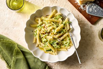 A plate of penne pasta with zucchini and grated cheese