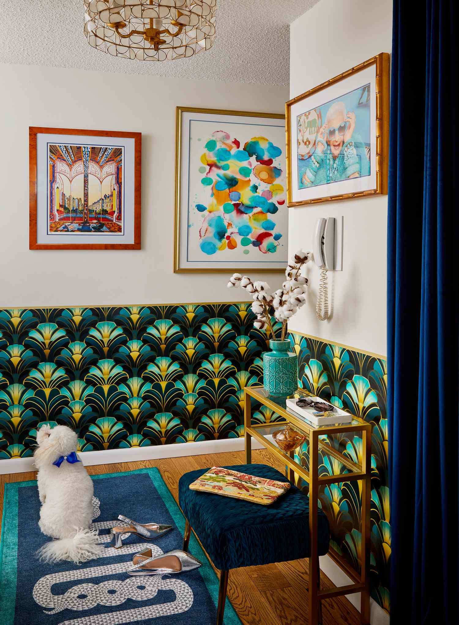 A cozy room with colorful wallpaper art on the wall a small seating area and a dog sitting on a rug
