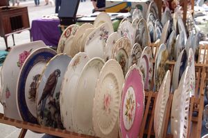 A display of decorative plates on a wooden rack at a market stall