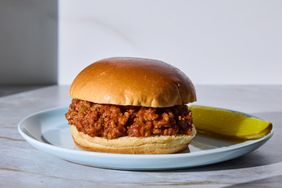 Sloppy joe sandwich on a plate with a pickle on the side