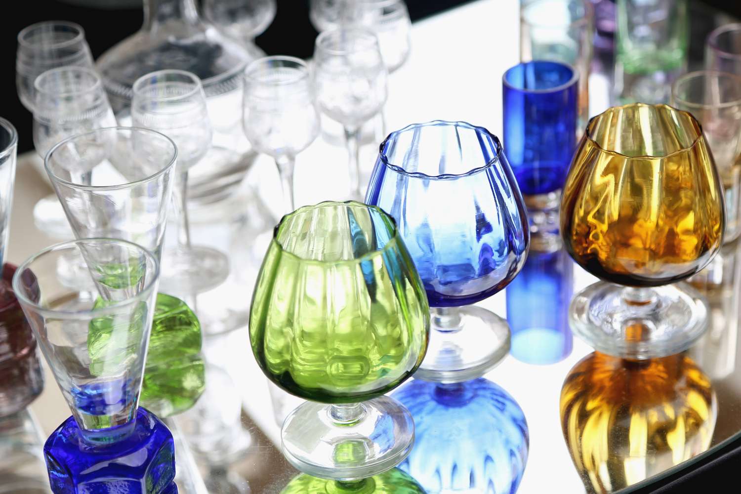 A selection of colored glassware on a reflective surface