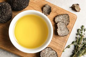 Fresh truffles, oil in bowl and thyme on light grey table