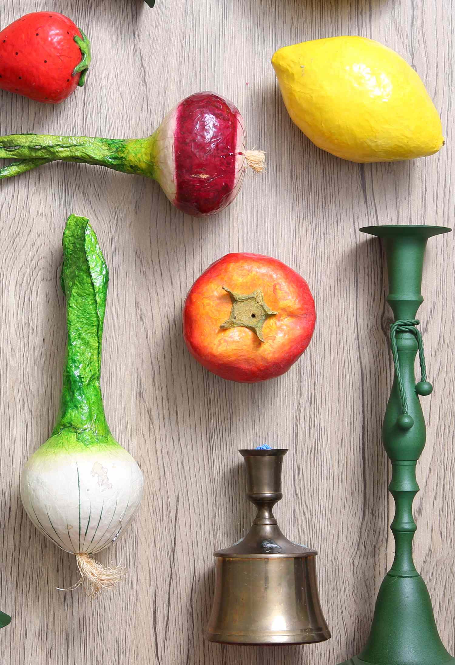 Assorted vegetables a candle holder and a bell arranged on a wooden surface