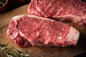 raw strip beef steak meat on wooden cutting board