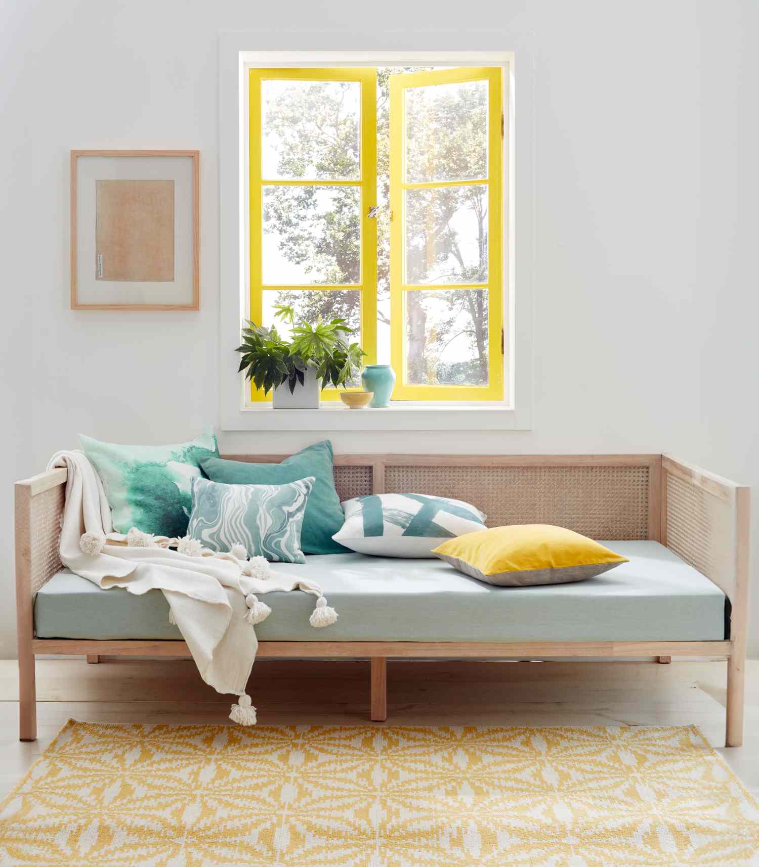 Daybed under a window with yellow and green throw pillows
