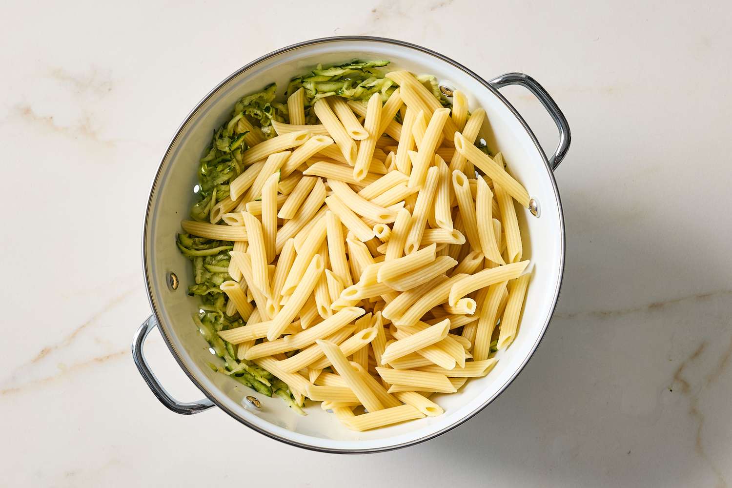 Penne pasta and shredded zucchini in a pot