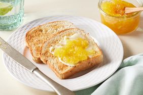 two pieces of toast with pineapple jam on it and glass container of jam