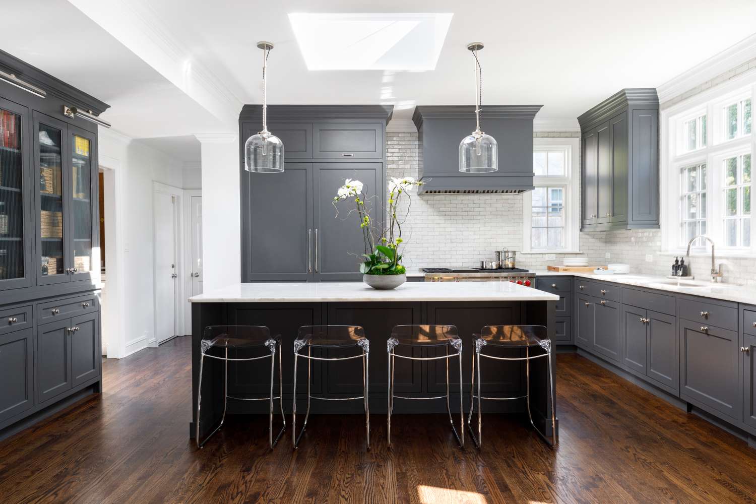 Modern kitchen with dark cabinetry, a central island with stools, and pendant lighting