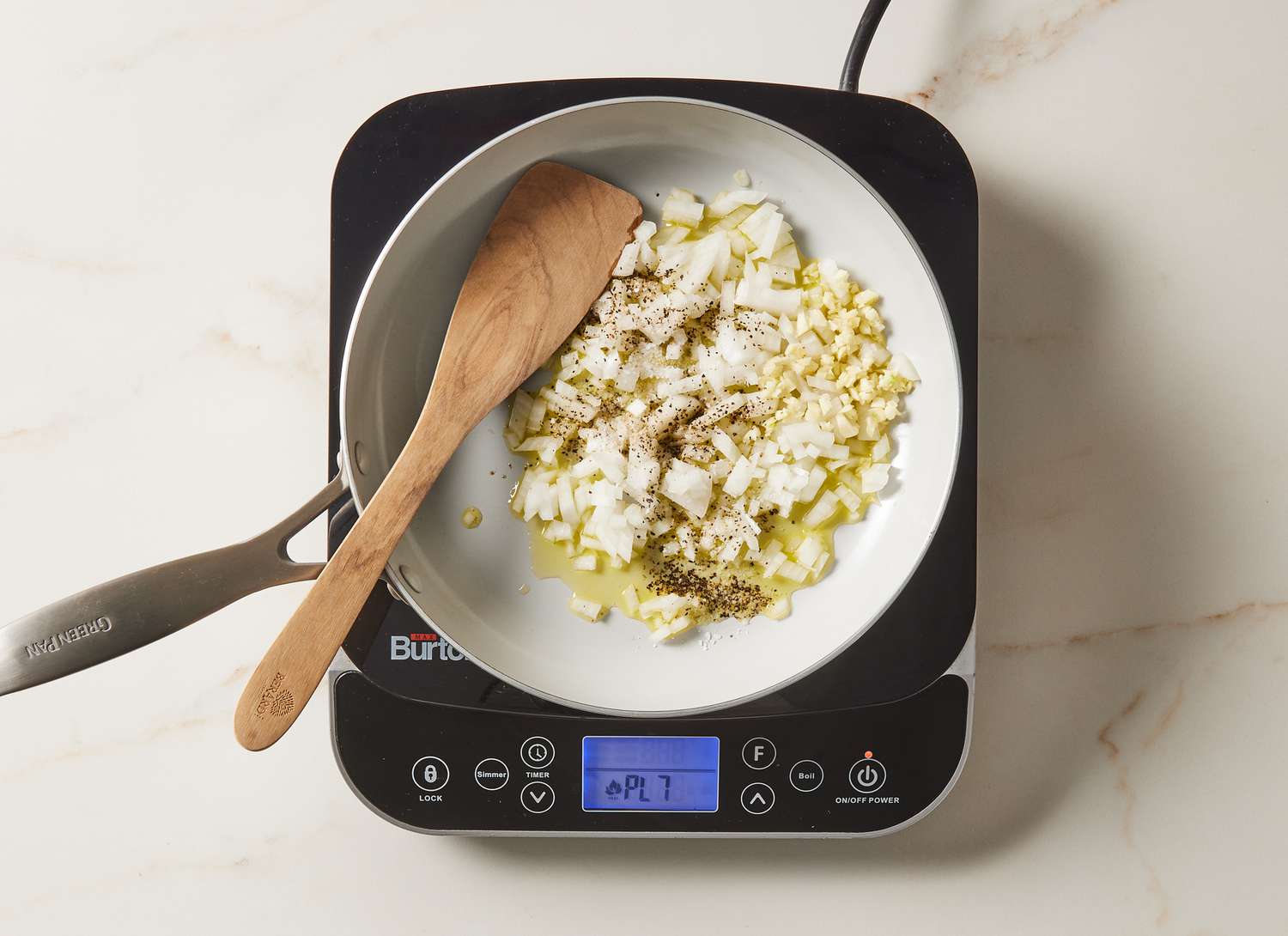 onions and spices sautÃ©ing in a skillet with a wooden spoon