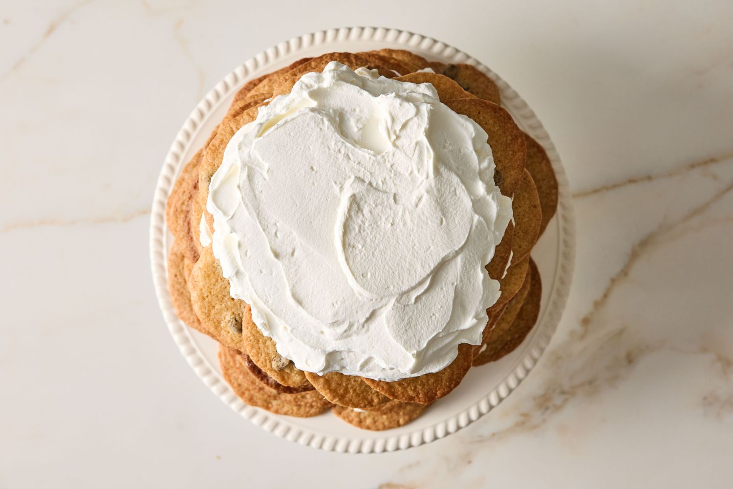 A layered dessert of cookies with cream topping on a plate