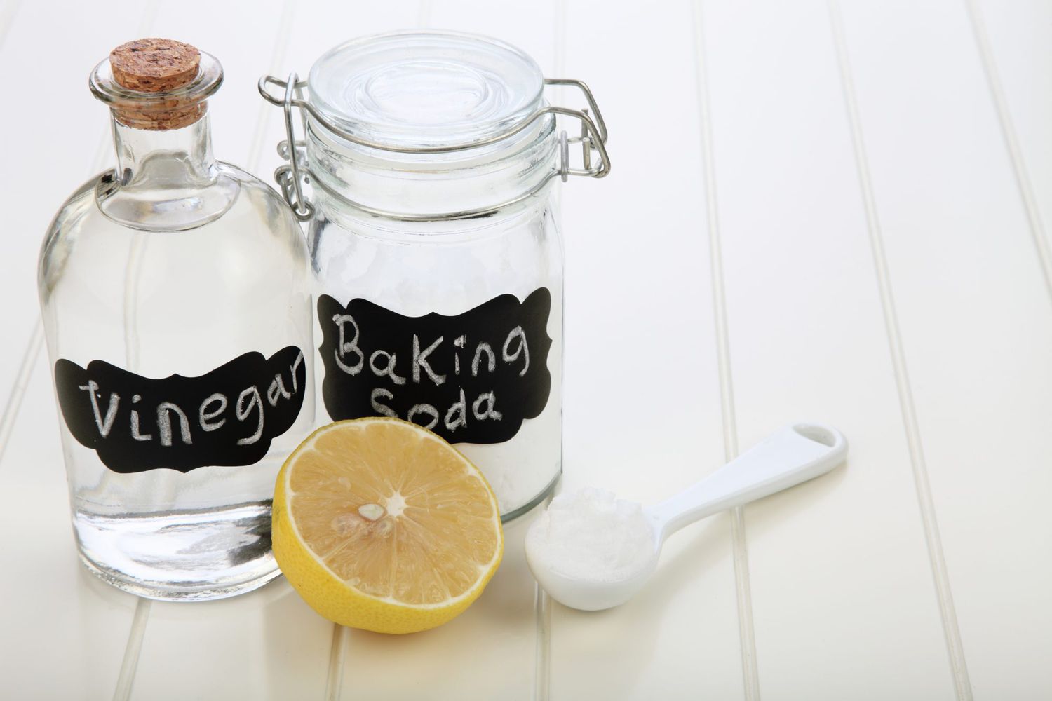 vinegar and baking soda next to lemon and measuring spoon