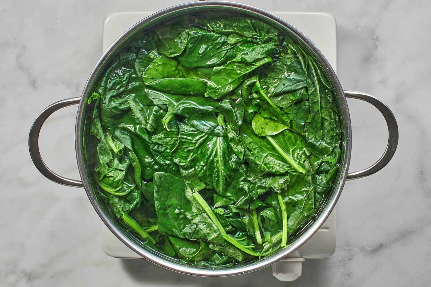 spinach in water in pot on burner