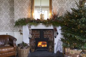 Fireplace decorated with garland and stockings Christmas tree with presents in a living room