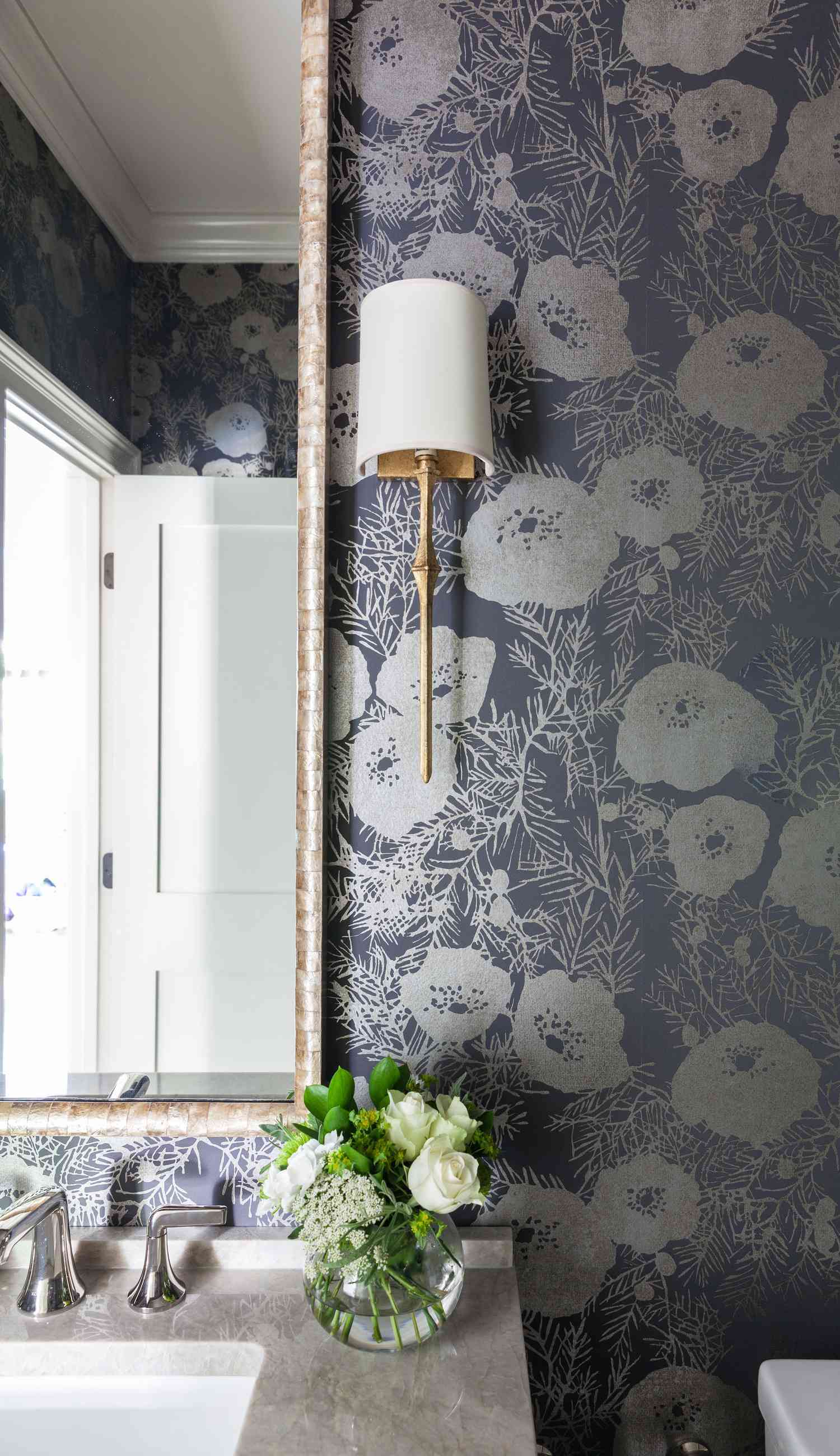Bathroom with floral wallpaper and a sconce