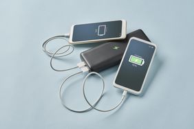 Two smartphones connected to a power bank one showing a low battery and the other at 92 charged