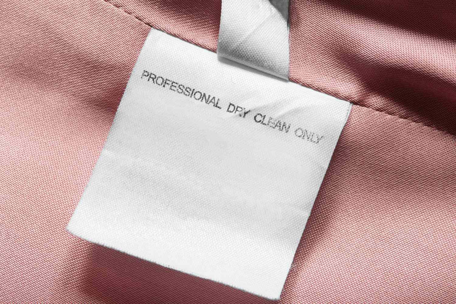 A fabric care label stating Professional Dry Clean Only on a pink garment