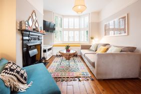A cozy living room with a large window sofas on either side a fireplace and a coffee table with a colorful rug beneath it