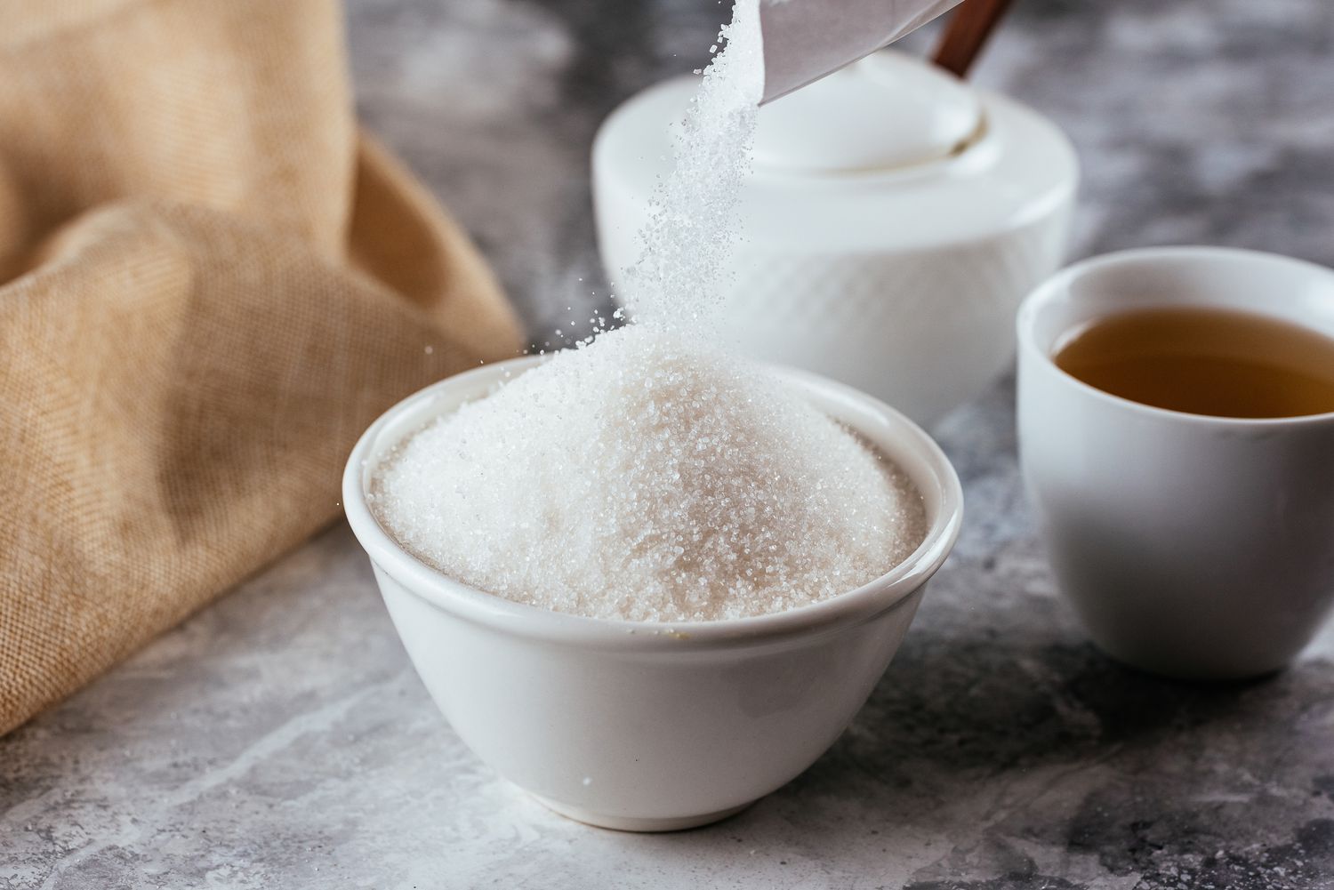 white sugar in a ceramic bowl on a marble background
