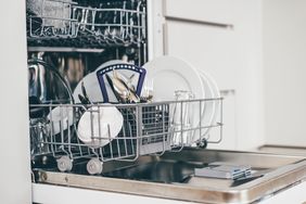 Open dishwasher with the lower rack loaded with dishes and cutlery