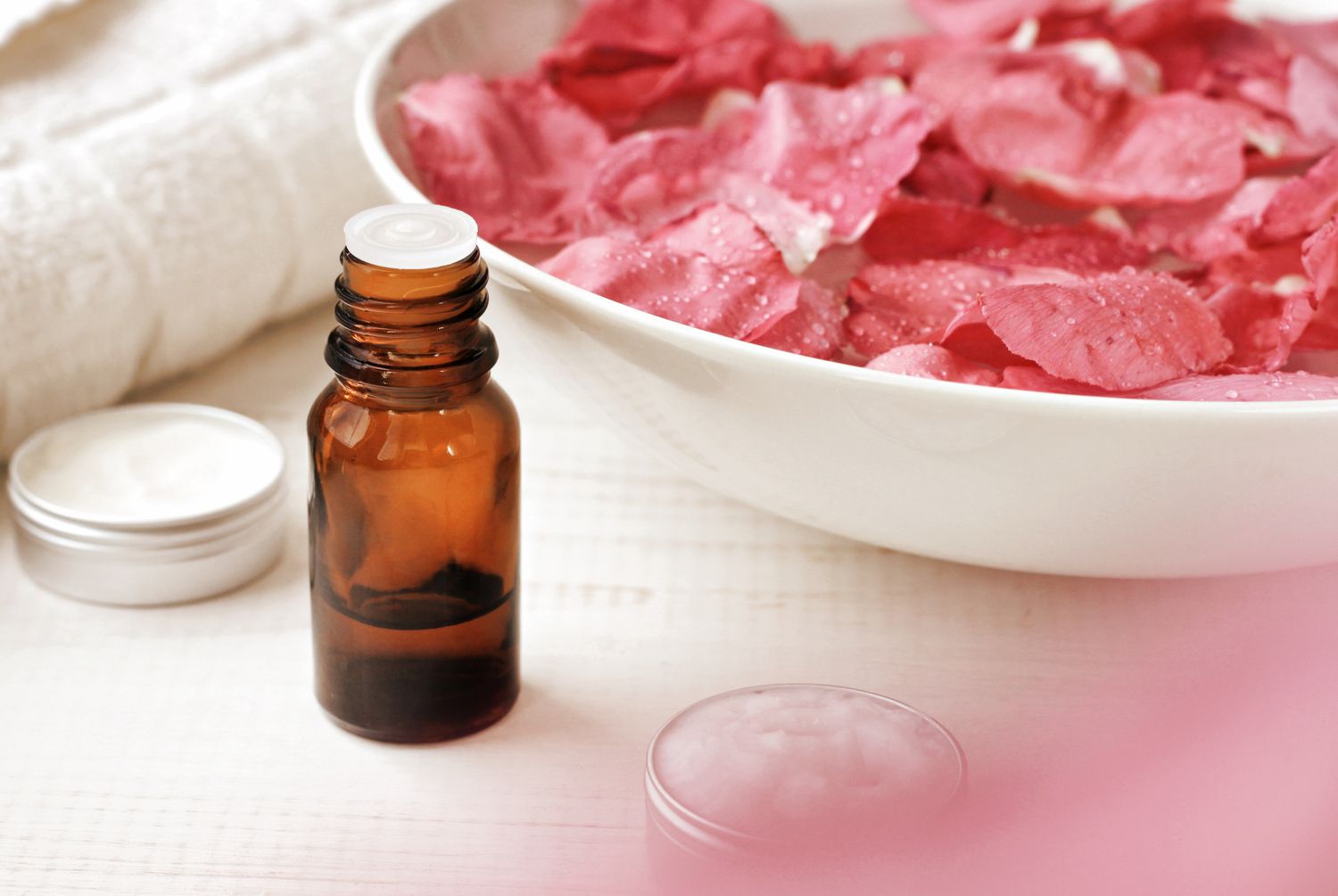 Making rose water with a small bottle, containers, and a bowl of rose petals