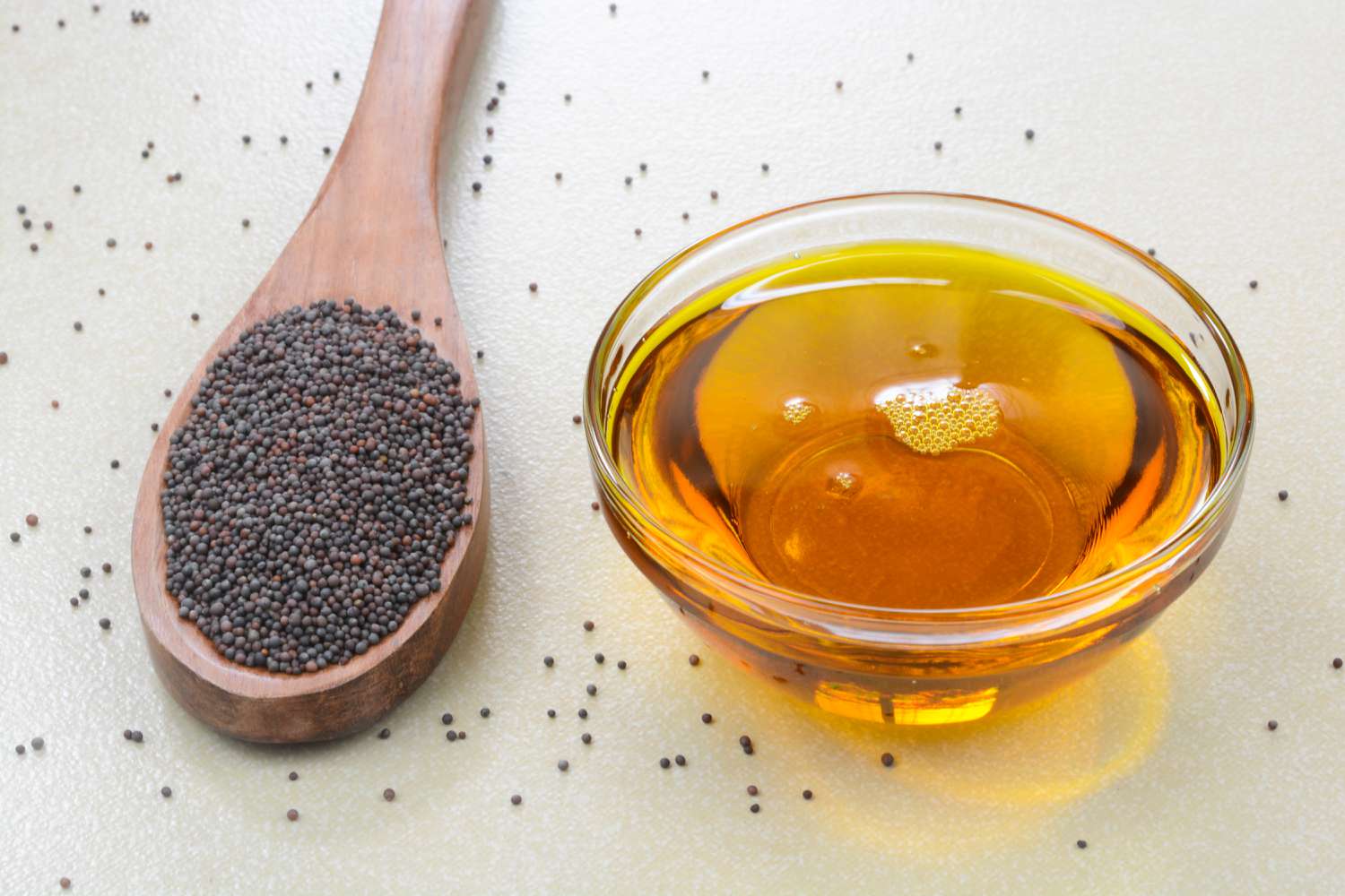 black mustard seeds in a spoon and mustard oil in a small bowl
