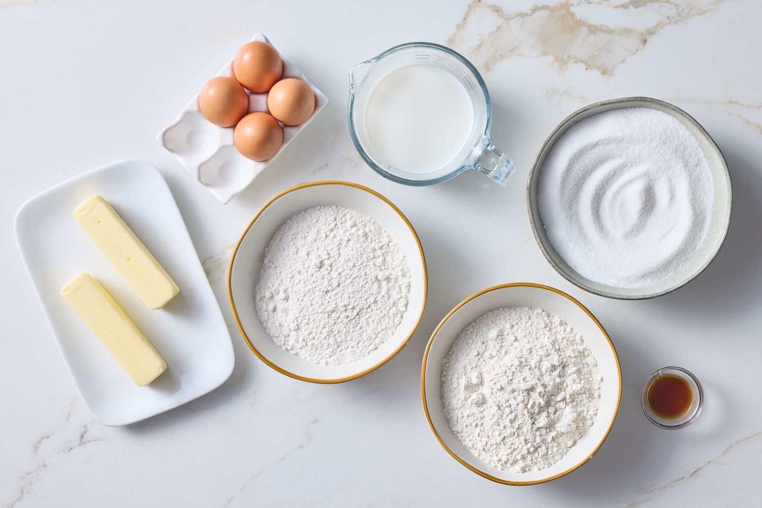 Ingredients for baking including eggs butter flour sugar milk and vanilla extract