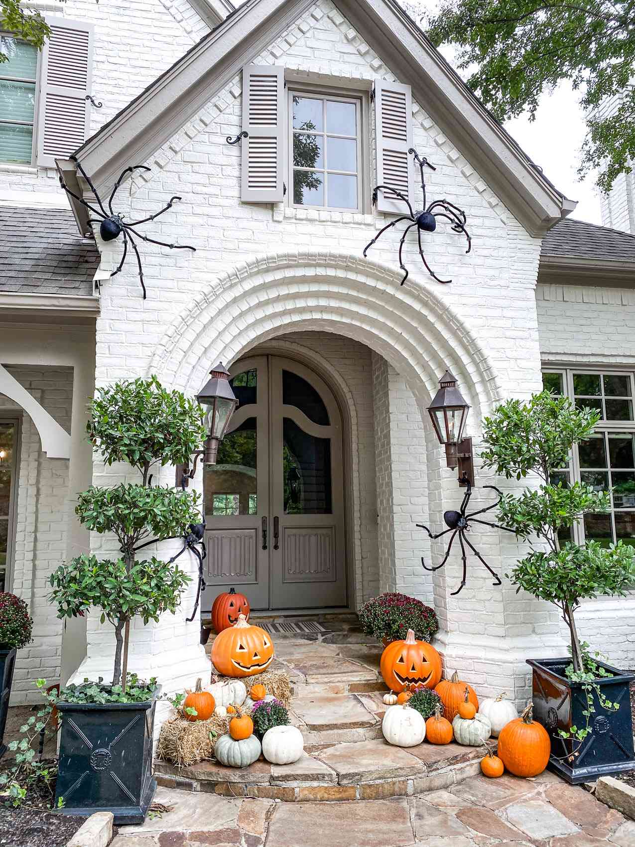 side view of fall porch with large spiders hay and pumpkins