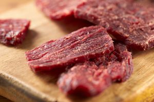 Slices of beef jerky laid on a wooden surface