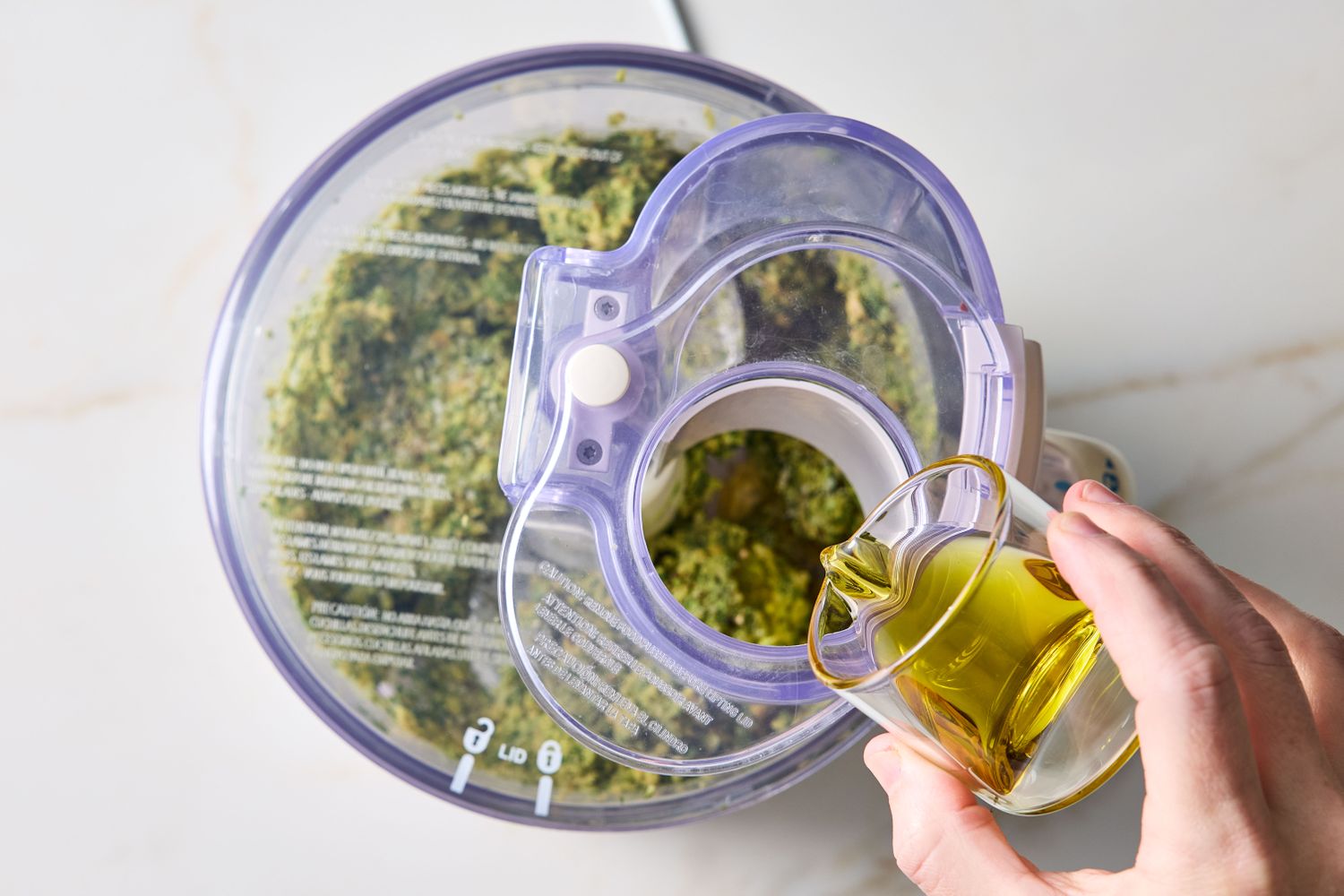 Adding oil to a food processor containing a green mixture