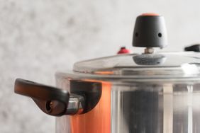 A closeup view of a pressure cooker lid with a handle and a valve
