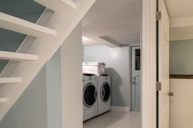 A basement laundry room with a washer dryer and staircase visible