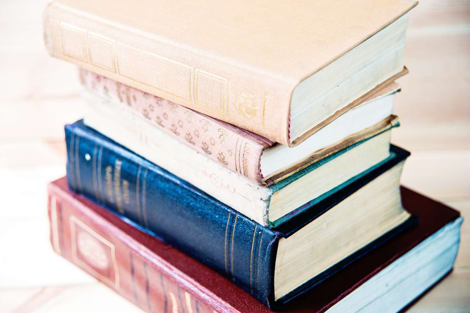 A stack of hardcover books of varying sizes placed on a surface arranged in a slight diagonal orientation