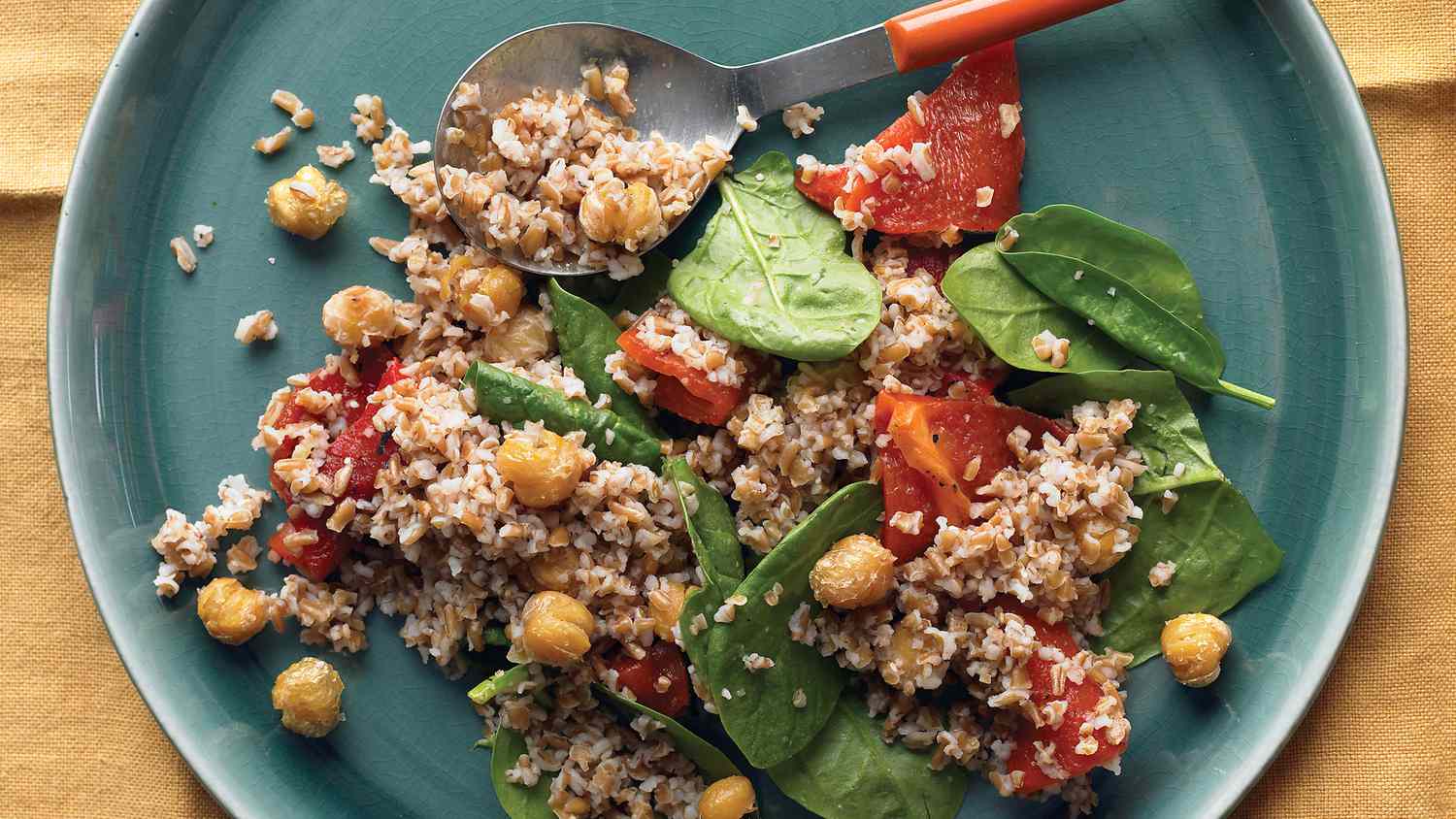 bulgur with chickpeas, spinach, and red peppers on blue-grey plate