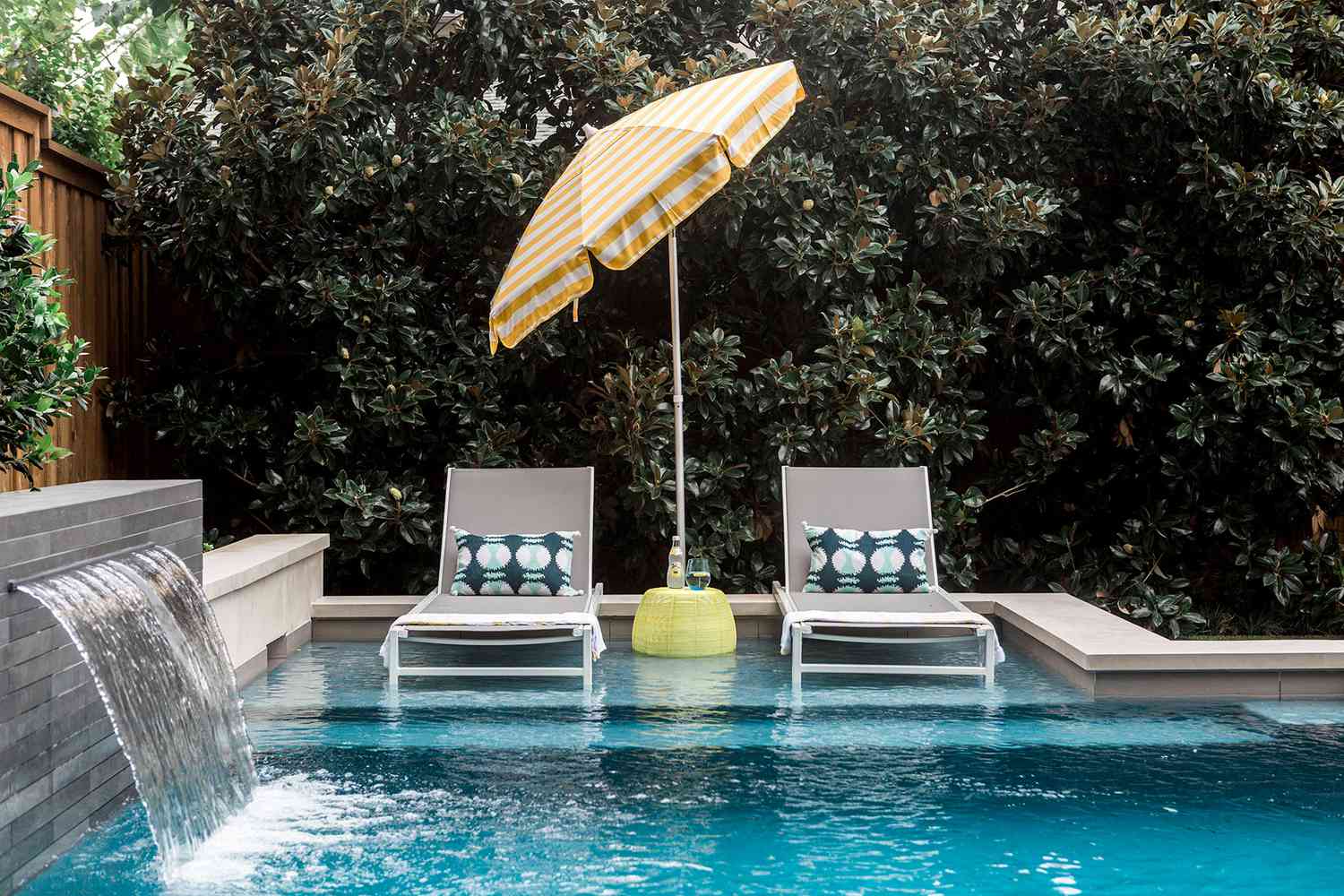 Outdoor pool with lounge chairs and small waterfall