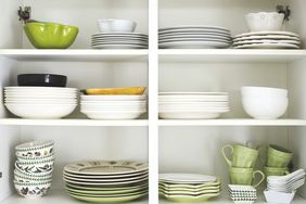 Tableware placed on a wooden shelf. Closeup of plates and dinnerware in a cupboard.